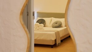 Quarto com cama, almofadas e um espelho refletindo o ambiente.
