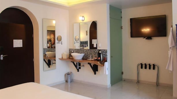 A modern bathroom with a large mirror, a sink, a vanity, a television, and a towel rack. - TRES79 Hotel Boutique Orizaba - Deluxe Room, 1 King (Orizaba)