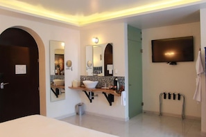 A modern bathroom with a large mirror, a sink, a vanity, a television, and a towel rack. - TRES79 Hotel Boutique Orizaba - Deluxe Room, 1 King (Orizaba)