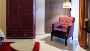 A hotel room with a large wardrobe, a tufted armchair, a small round table, and a lamp. - TRES79 Hotel Boutique Orizaba - Deluxe Room, 1 King (Orizaba)