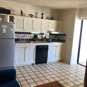 A compact kitchen with white cabinets, a dishwasher, and a tiled backsplash. - Cozy Studio condo in Terrasol with beautiful ocean view. (Cabo san Lucas)