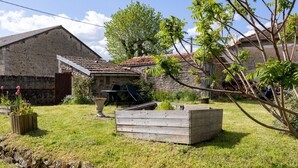 A rustic stone building with a tiled roof, a wooden bench, and a raised garden bed. - Gîte La Traverse: Private Terrace, Private Garden, and Wi-Fi in Persac (Persac)