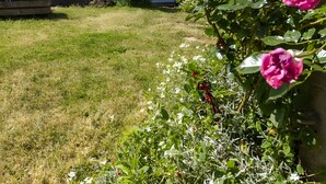A house with a tiled roof, a chimney, a garden with flowers, and a wooden pergola. - Gîte La Traverse: Private Terrace, Private Garden, and Wi-Fi in Persac (Persac)