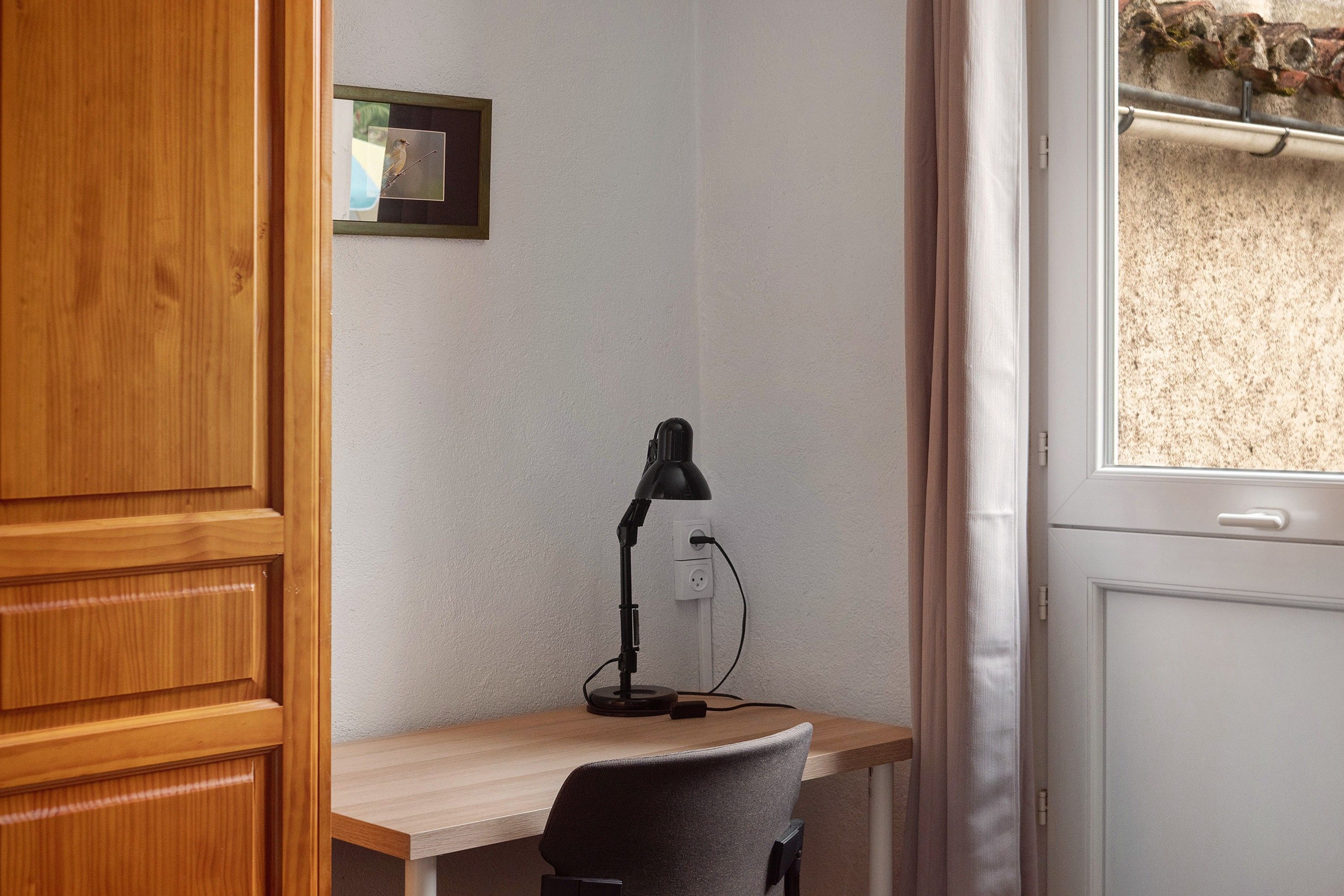 Ein Büro im Eck mit Schreibtisch, Stuhl und Schreibtischlampe.