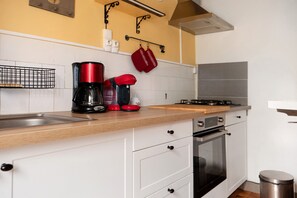 A kitchen with a wooden countertop, a coffee maker, a kettle, and a stove.