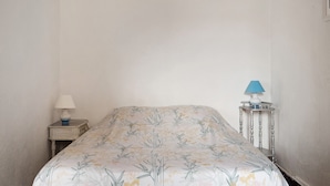 A single bed with a floral bedspread in a room with plain walls.