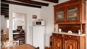 A kitchen with wooden cabinets, a white refrigerator, a microwave, and a dining table with chairs.