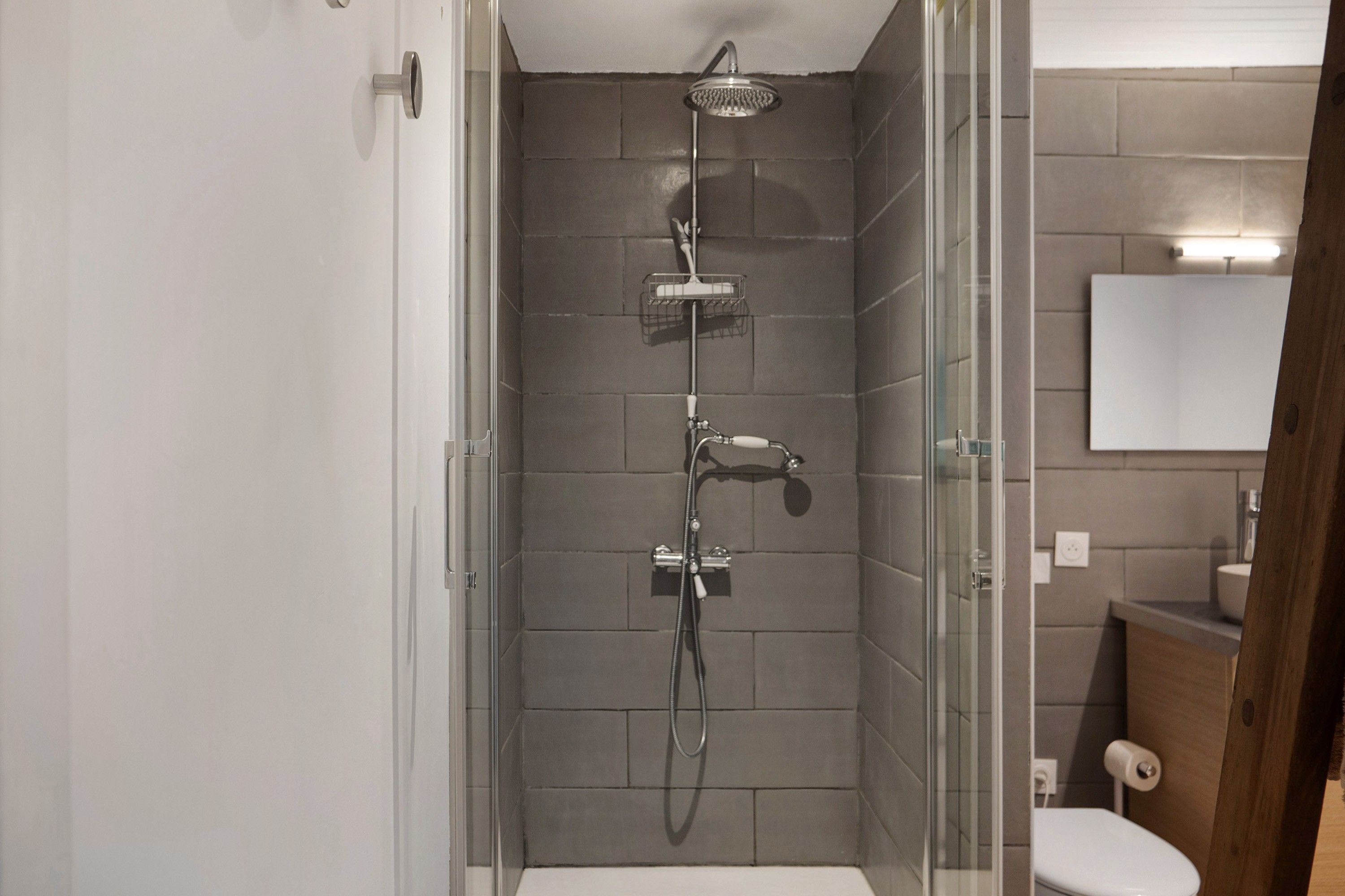 A modern bathroom with a glass-enclosed shower, a toilet, and a sink with a mirror above.
