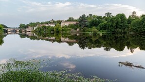 A calm river with a bridge, buildings, and lush greenery. - Gîte La Traverse: Private Terrace, Private Garden, and Wi-Fi in Persac (Persac)