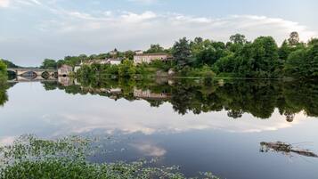 Ein ruhiger Fluss mit einer Brücke, Gebäuden und üppigem Grün.