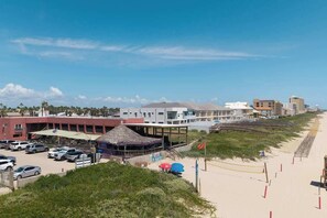 Ein Küstenhotel mit Blick auf den Strand, einem Parkplatz und einem Restaurant mit Reetdach.