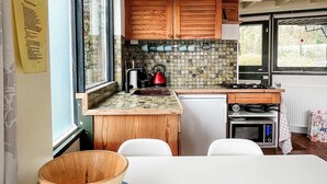 Une cuisine compacte avec des meubles de rangement en bois, une cuisinière à gaz, un four à micro-ondes et un petit réfrigérateur.