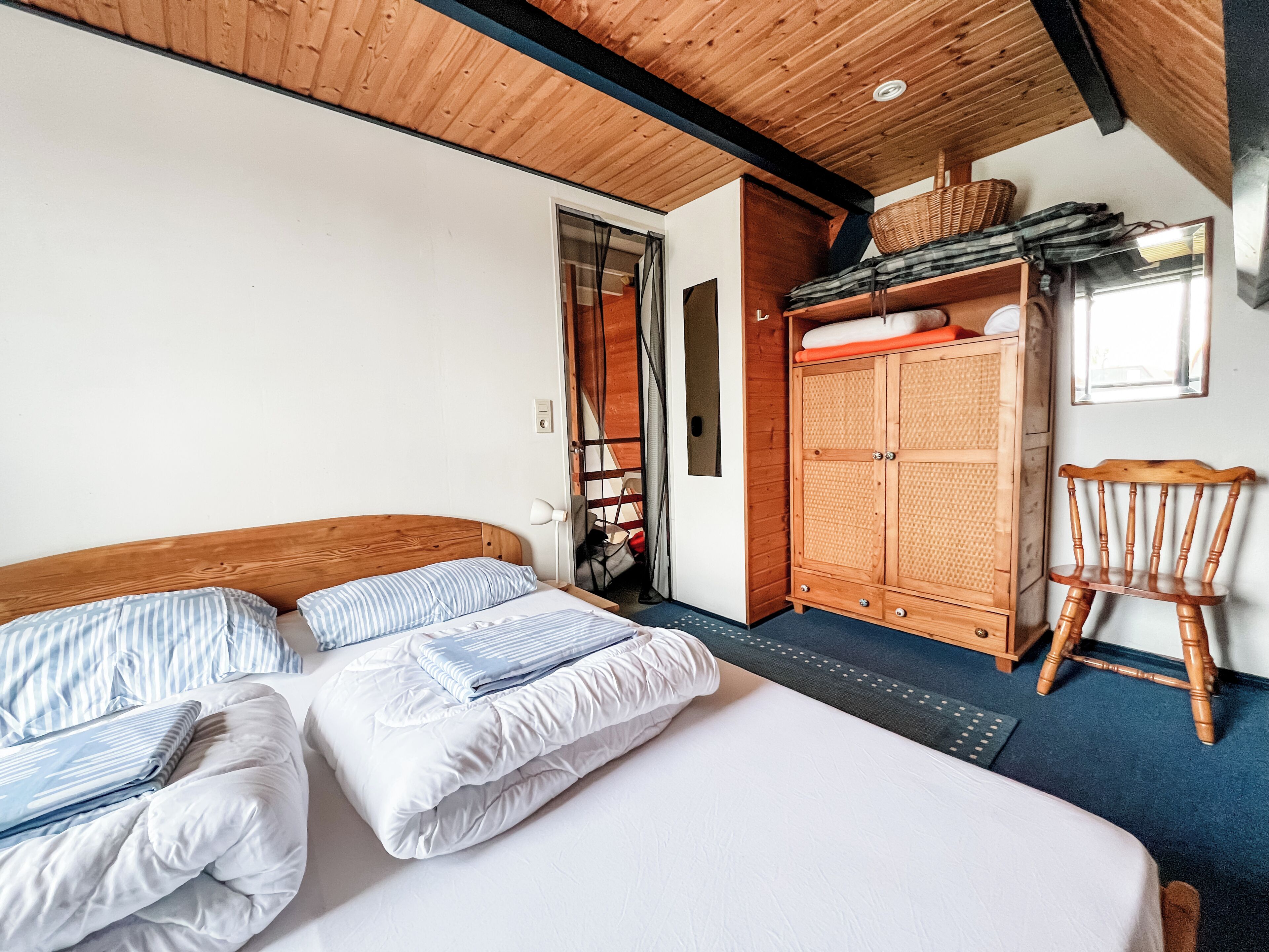 Una camera da letto con un letto, un armadio, una sedia e una porta che dà su un'altra stanza.