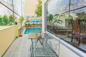Un balcon avec une piscine, des plantes en pot et une vue sur une fresque murale aux couleurs vives.