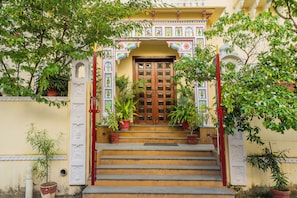 A building entrance with a wooden door, steps, and potted plants. - Vasant Vilas 'A Boutique Hotel' (Udaipur)