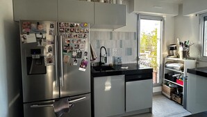 Cuina moderna amb nevera d'acer inoxidable, rentaplats integrat i finestra que ofereix vistes a l'exterior.