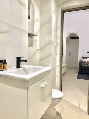 A modern bathroom with a white sink, black faucet, and a toilet. - Suite Verde Medina Tangier (Tanger)