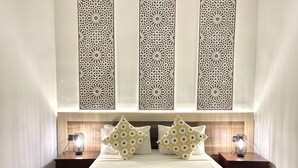 Una habitación de hotel con una cama bien hecha, paneles decorativos en la pared, dos mesitas de noche con lámparas y un cabecero de madera.