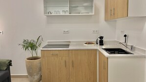 Una cocina compacta con microondas integrado, un lavabo y un armario con estantes de vidrio en la parte superior.