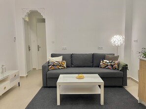 A modern living room with a grey sofa, a white coffee table, and a decorative lamp. - Suite Verde Medina Tangier (Tanger)