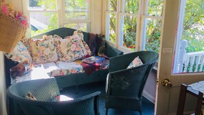 A cozy room with a wicker sofa, a chair, and a table with a floral cushion.