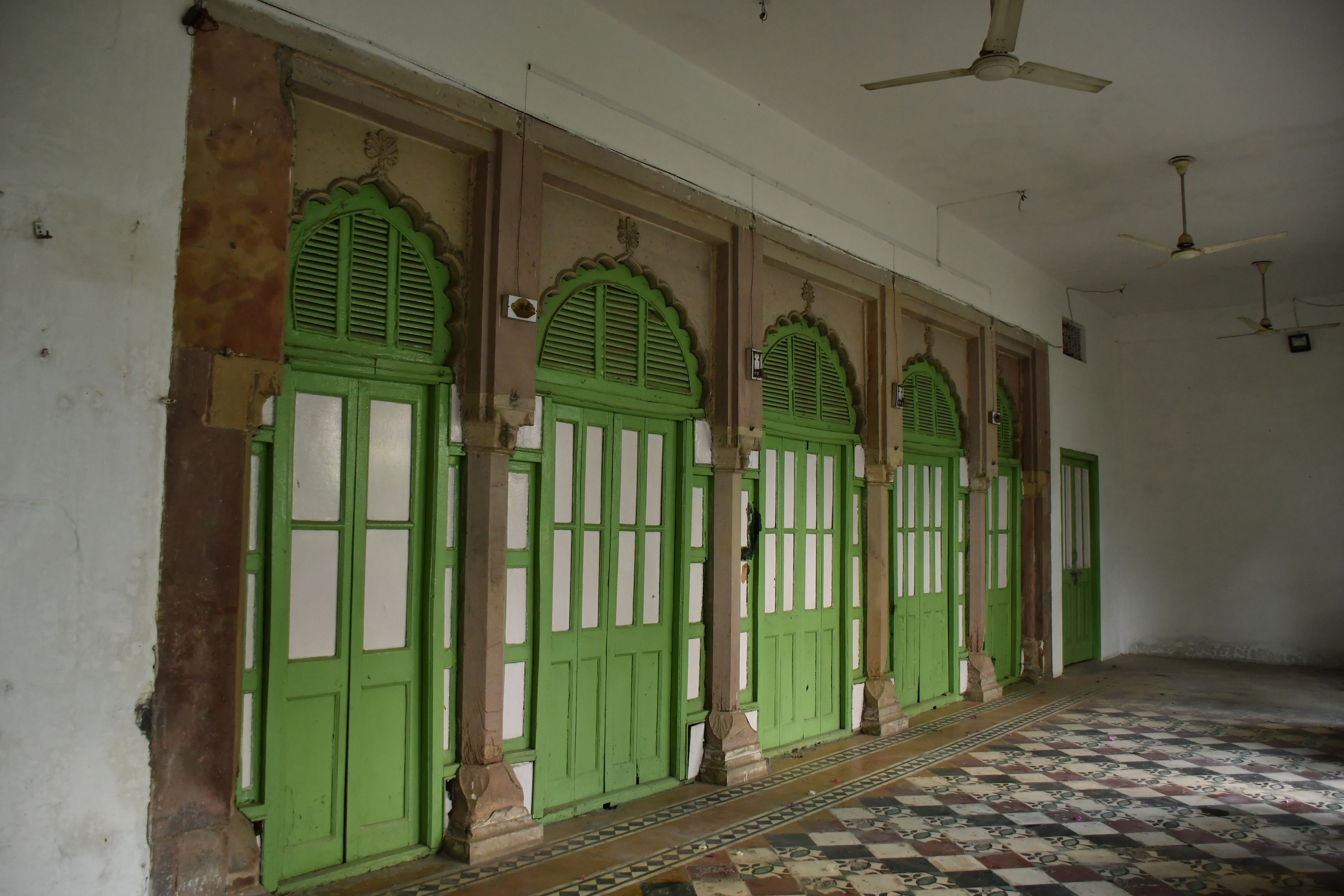 A corridor with green doors and a tiled floor.