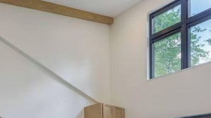 Eine moderne Küche mit Kochinsel, Barhocker, Holzschränken und einem großen Fenster.