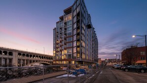A multi-story building with a modern architectural design, featuring a prominent corner structure and a series of balconies. - Modern Flats Retreat  Free Parking & Gym (Cleveland)