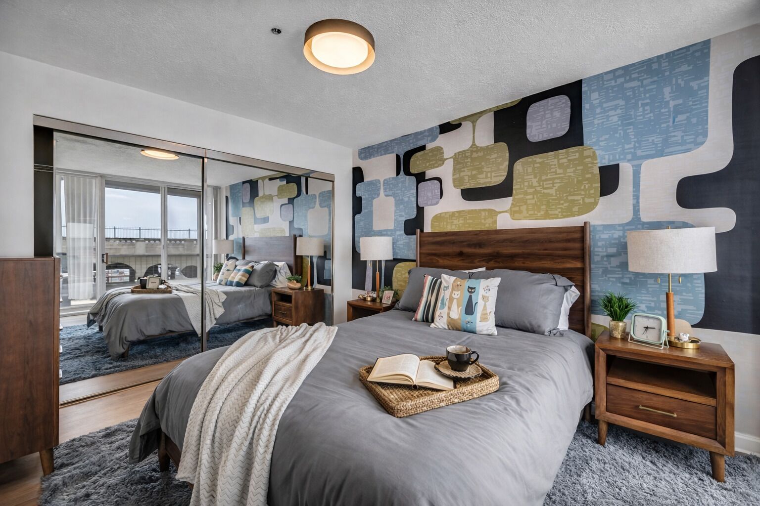 A modern bedroom with a large bed, bedside tables, a mirror, and abstract wall art.