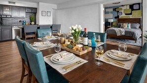 A dining room with a wooden table set for six, surrounded by teal chairs. - Modern Flats Retreat  Free Parking & Gym (Cleveland)
