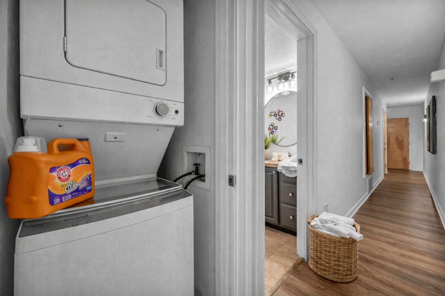 A laundry area with a washing machine, a detergent bottle, and a basket.