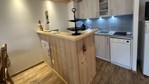 A compact kitchen with wooden cabinets, a central island, a dishwasher, and a microwave. - Ground floor, tv, 35m², Villard de Lans (Villard-de-Lans)