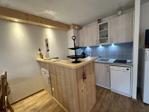 A compact kitchen with wooden cabinets, a central island, a dishwasher, and a microwave. - Ground floor, tv, 35m², Villard de Lans (Villard-de-Lans)