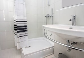 Ein Badezimmer mit einer weißen Badewanne, einer Dusche, einem Waschbecken mit Spiegel und einem gestreiften Handtuch.