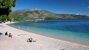 A beach with clear water, people sunbathing, and mountains in the background. - Modern Flat With sea View (Orebic)