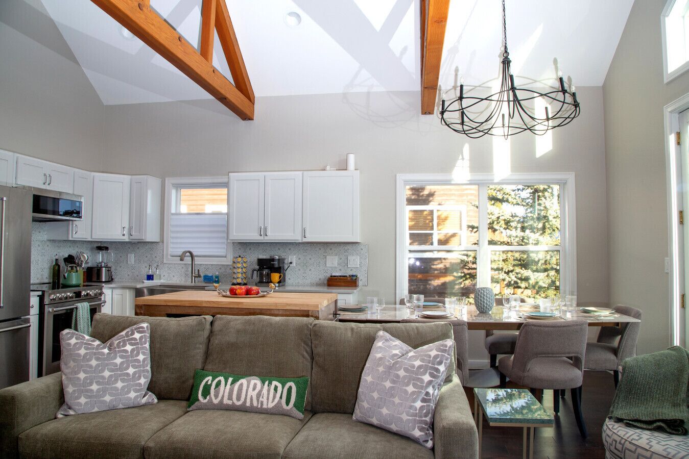 Una cocina moderna con armarios blancos, un comedor con mesa y sillas, y una sala de estar acogedora con un sofá.