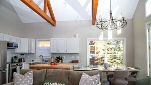 Una cocina moderna con armarios blancos, un comedor con mesa y sillas, y una sala de estar acogedora con un sofá.
