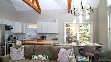 Una cocina moderna con armarios blancos, un comedor con mesa y sillas, y una sala de estar acogedora con un sofá.