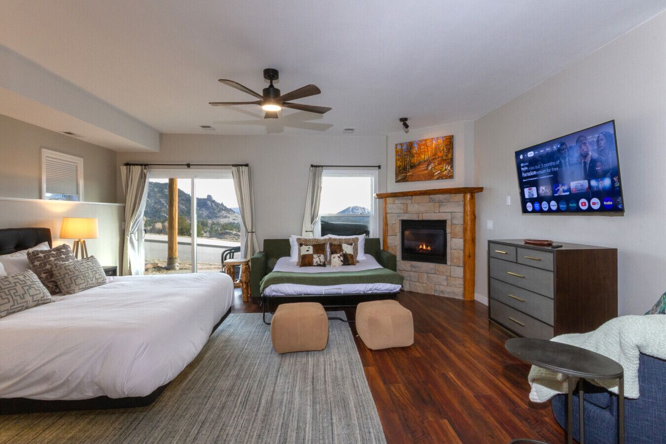 Un dormitorio con cama, sofá, televisor, chimenea y vistas al exterior.