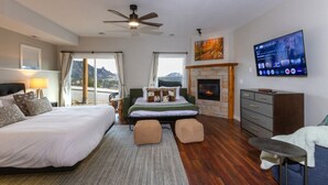 Un dormitorio con cama, sofá, televisor, chimenea y vistas al exterior.