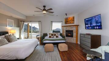 Un dormitorio con cama, sofá, televisor, chimenea y vistas al exterior.