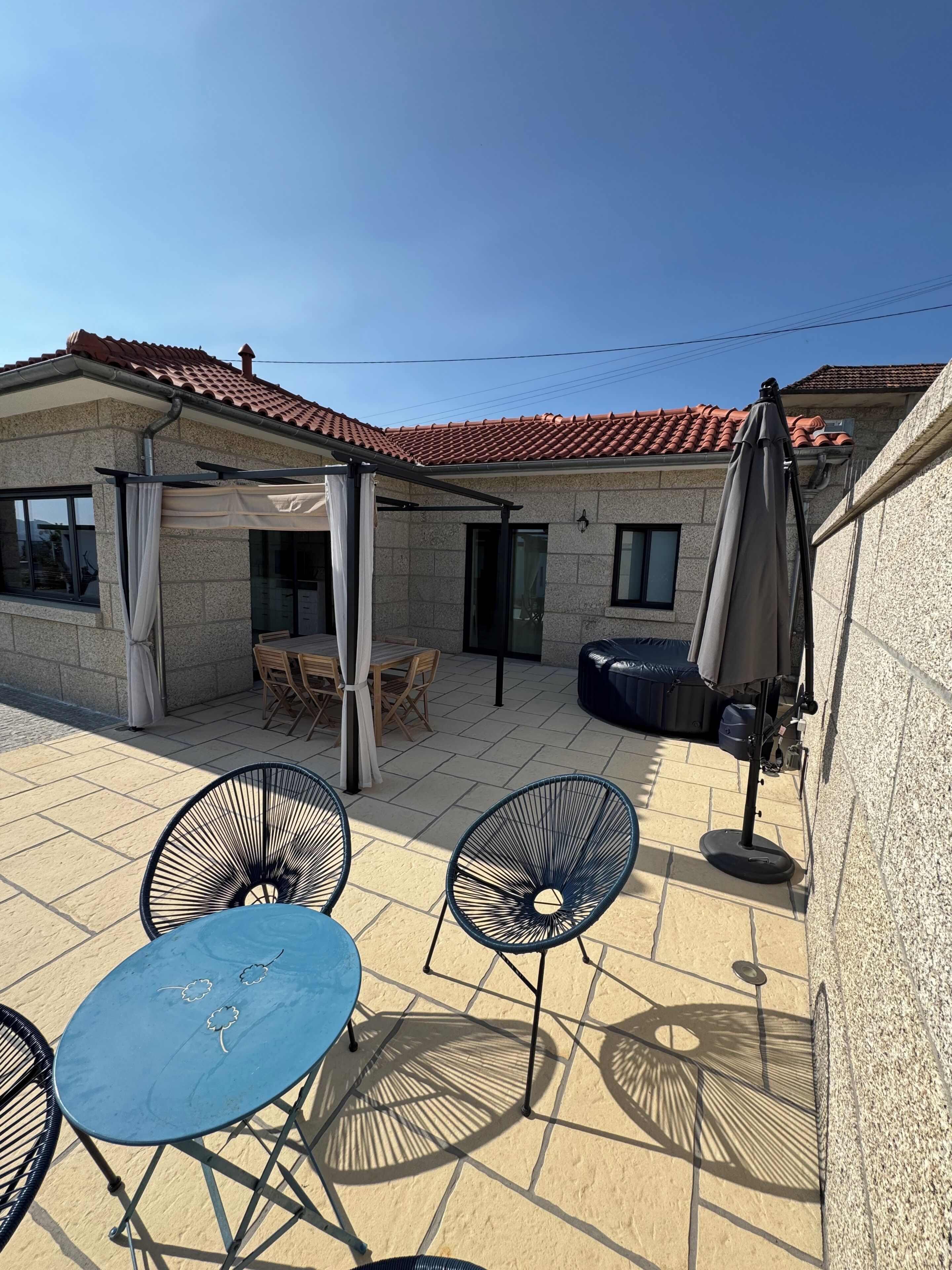 A patio with outdoor furniture, a covered seating area, and a building with a tiled roof.