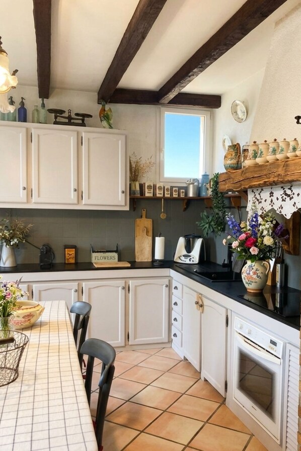 A kitchen with white cabinets, a black countertop, a window, and a tiled floor. - Maison de maître with swimming pool - Near Toulouse (Launaguet)