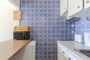Eine Küche mit blauen und weißen gemusterten Fliesen, einer Mikrowelle, einem Toaster und einem Holzklotz mit motivierenden Sprüchen.