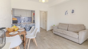 A modern kitchen with a dining area, a beige sofa, and a door leading to another room. - #374 Cozy & Bright Stay | City Comfort (Albufeira)