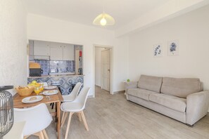 Eine moderne Küche mit Essbereich, ein beiges Sofa und eine Tür zu einem anderen Raum.