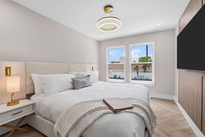 Una camera da letto moderna con un letto, un comodino, una lampada e un'ampia finestra.