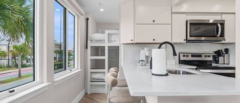 A modern kitchen with a large island, built-in appliances, and a view of the street.