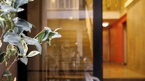 A modern building with a glass entrance, a staircase, and a red wall. - Apartment 'Residenza San Nicolò Treviso' with Private Terrace, Wi-Fi and Air Conditioning (Treviso)