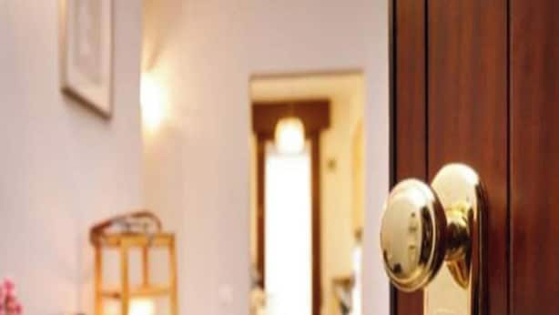 A wooden door with a brass doorknob, a framed picture on the wall, and a glimpse of a room with a wooden floor and a small table. - Apartment 'Residenza San Nicolò Treviso' with Private Terrace, Wi-Fi and Air Conditioning (Treviso)